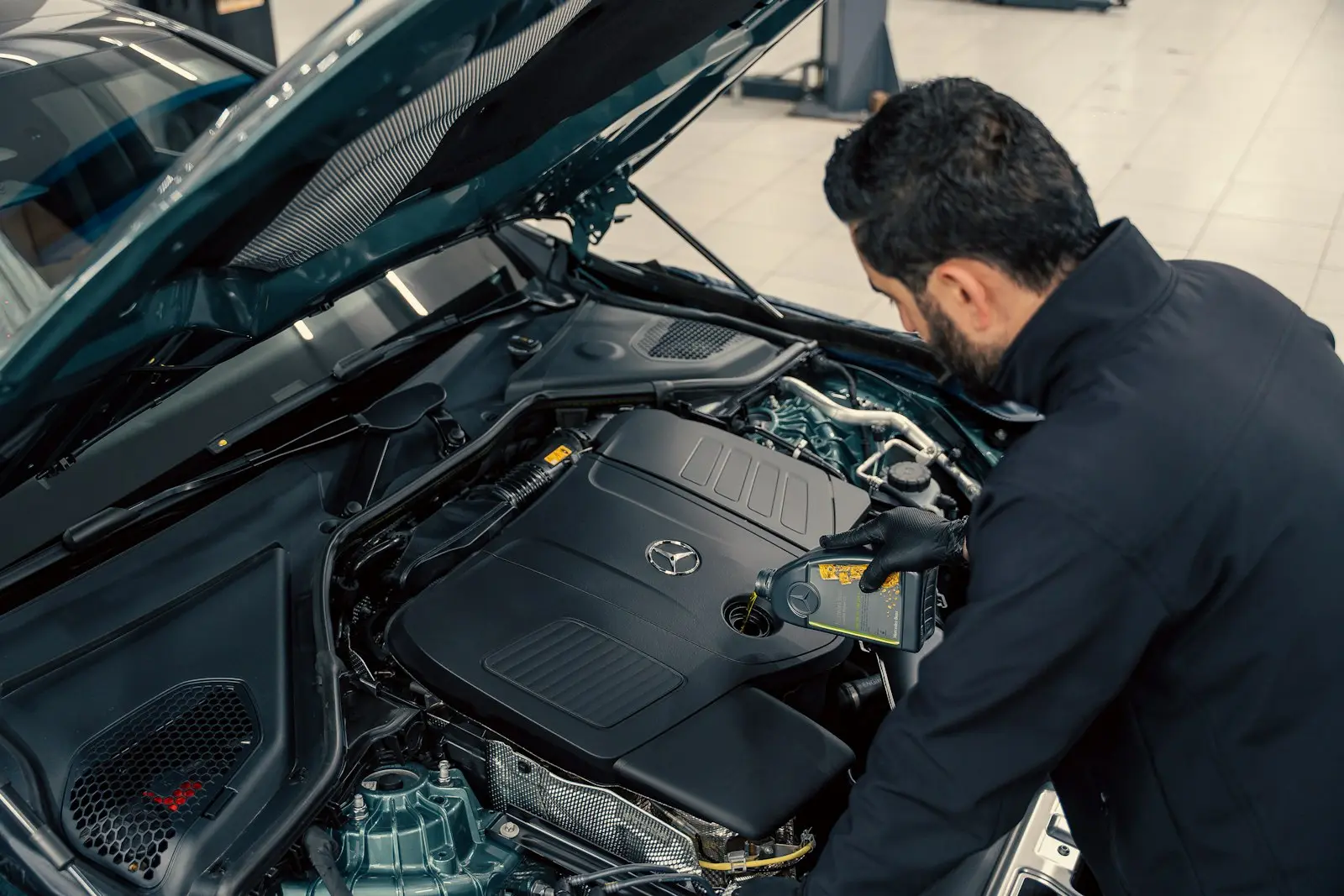 Mecánico revisando el motor de un auto con el cofre abierto