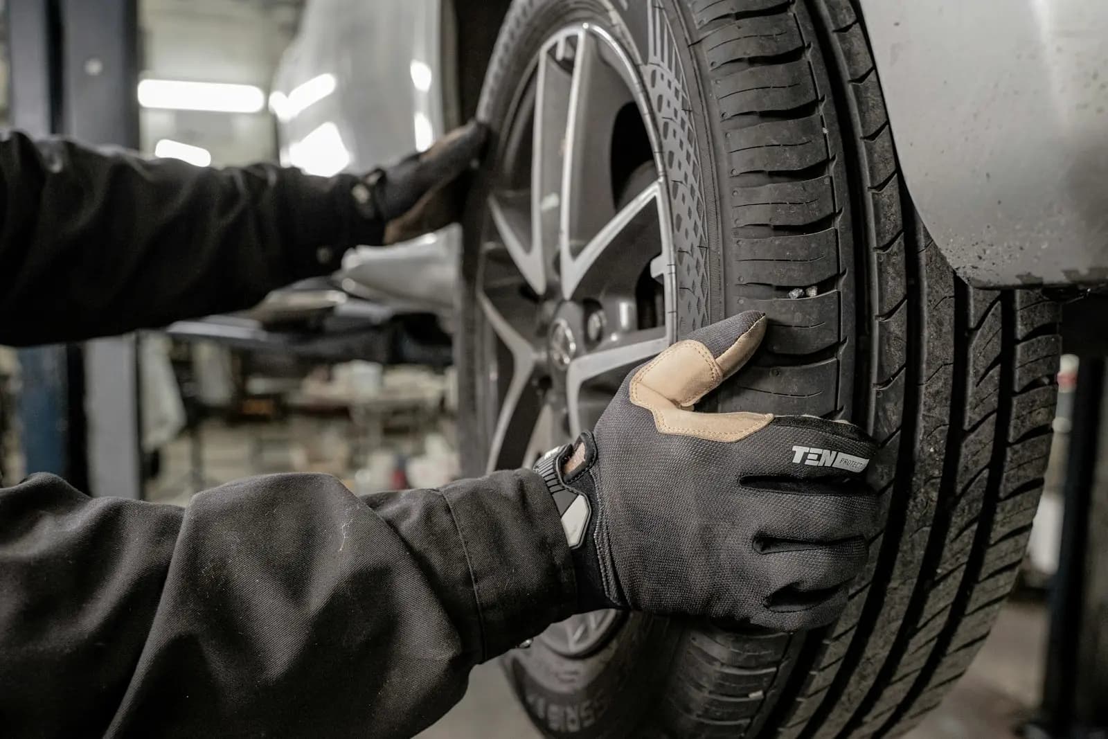 Técnico con guantes revisando la llanta de un auto en el taller